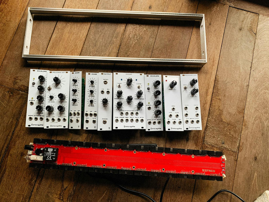 Componentes de sintetizador modular sobre piso de madera — qué módulos Eurorack comprar primero