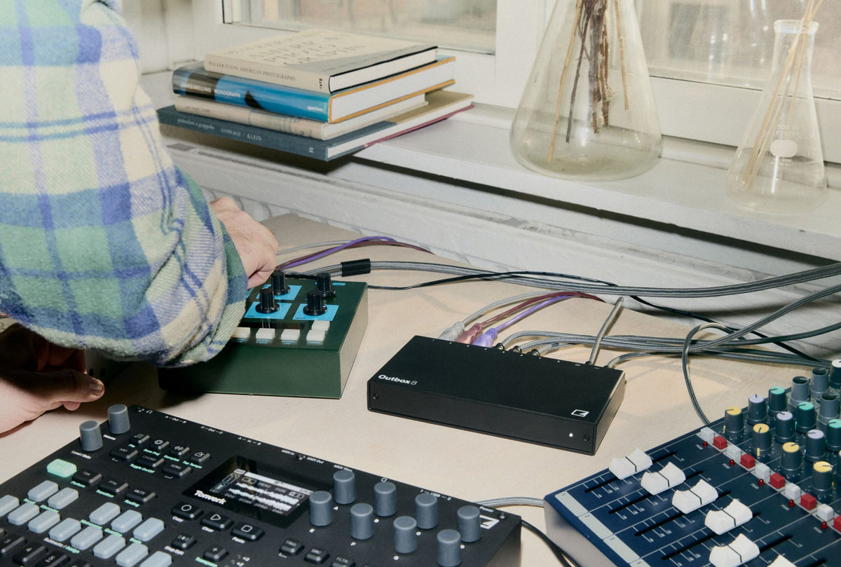 Elektron Outbox 8 sobre una mesa junto a una máquina Elektron Tonverk, un sintetizador y una mezcladora, conectado como interfaz de audio