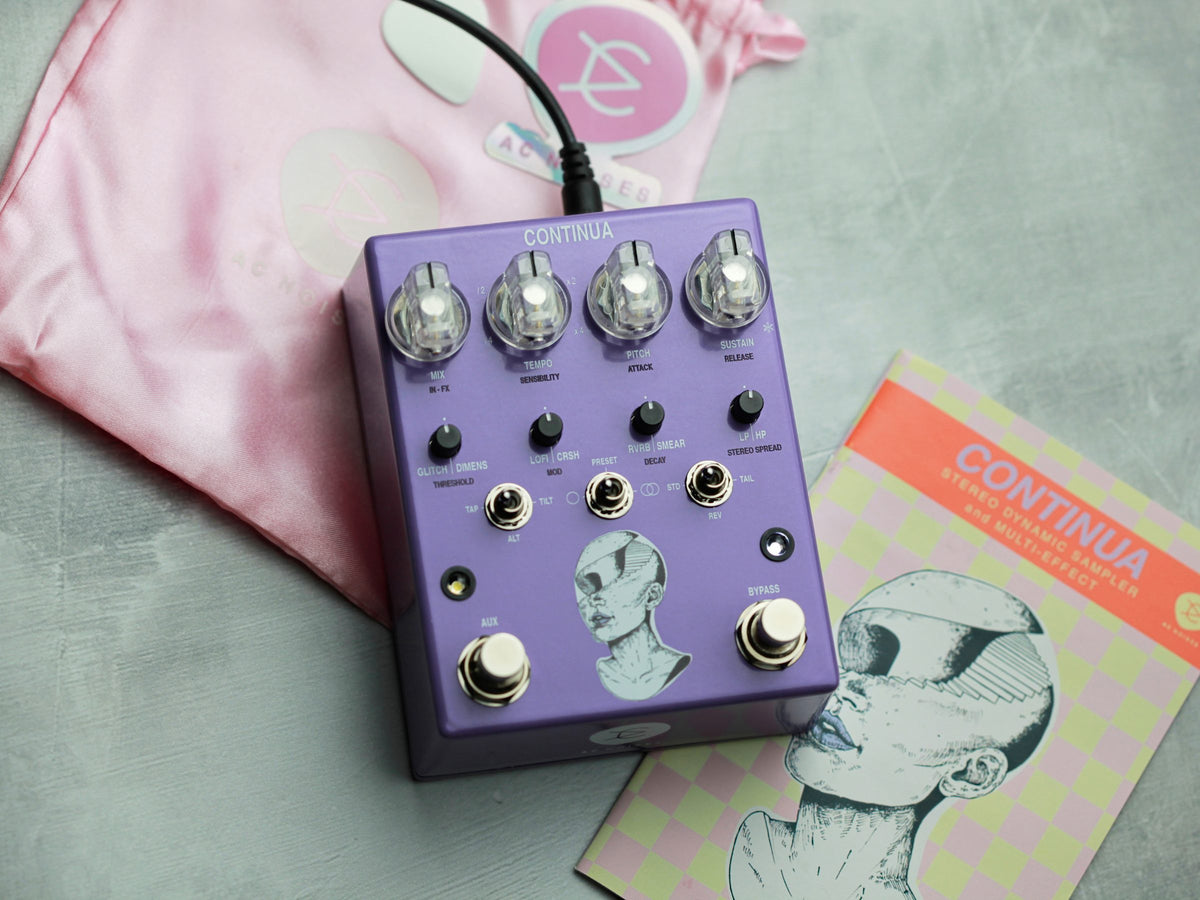 Pedal AC Noises Continua sobre una bolsa de tela rosada y su folleto