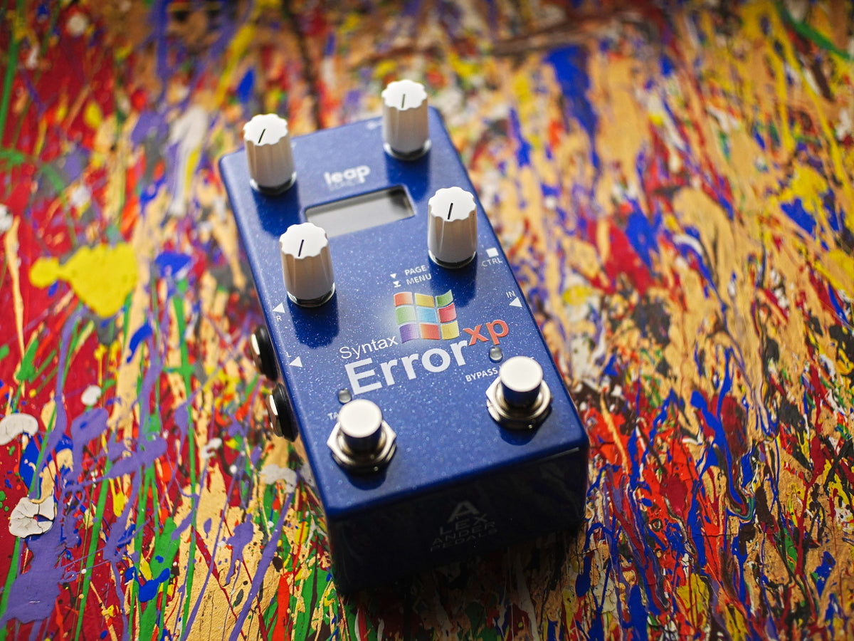 Pedal Alexander Syntax Error XP, azul, sobre una tela salpicada de pintura de colores