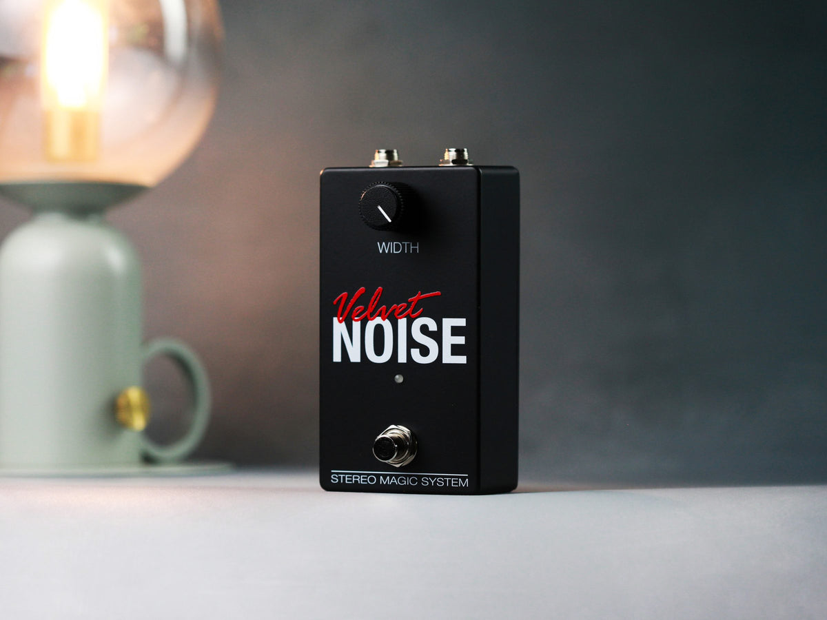 Pedal Alexander Velvet Noise, negro con una sola perilla, junto a una lámpara