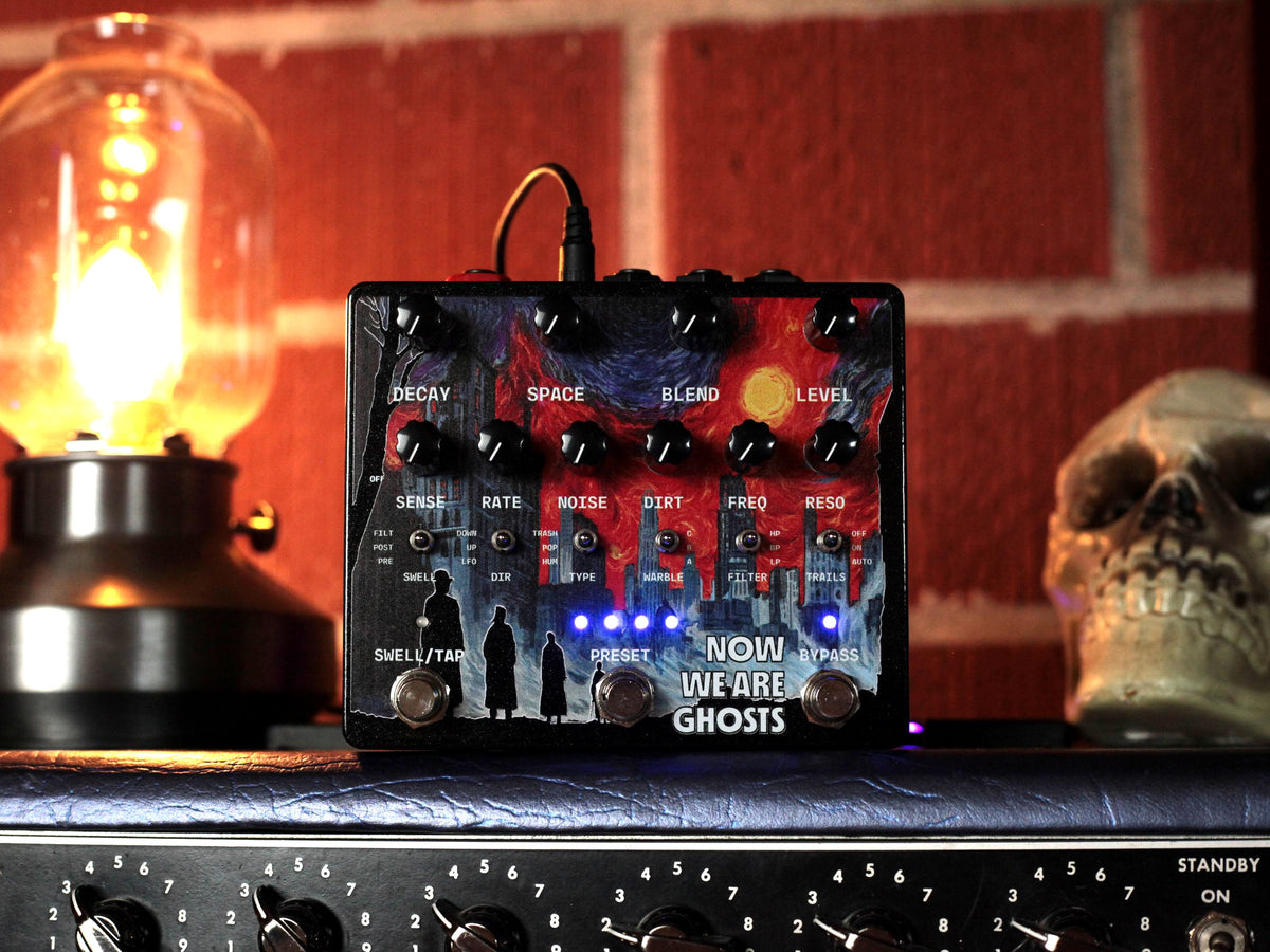 Pedal Alexander Now We Are Ghosts sobre un amplificador, junto a una lámpara y una calavera