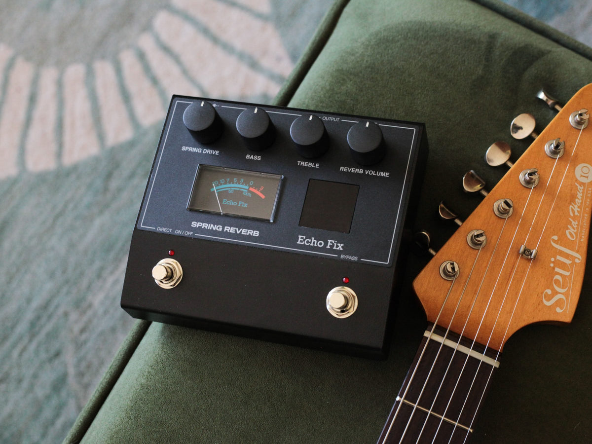 Pedal Echo Fix EF-P2 Spring Reverb sobre un sillón verde, junto al mástil de una guitarra