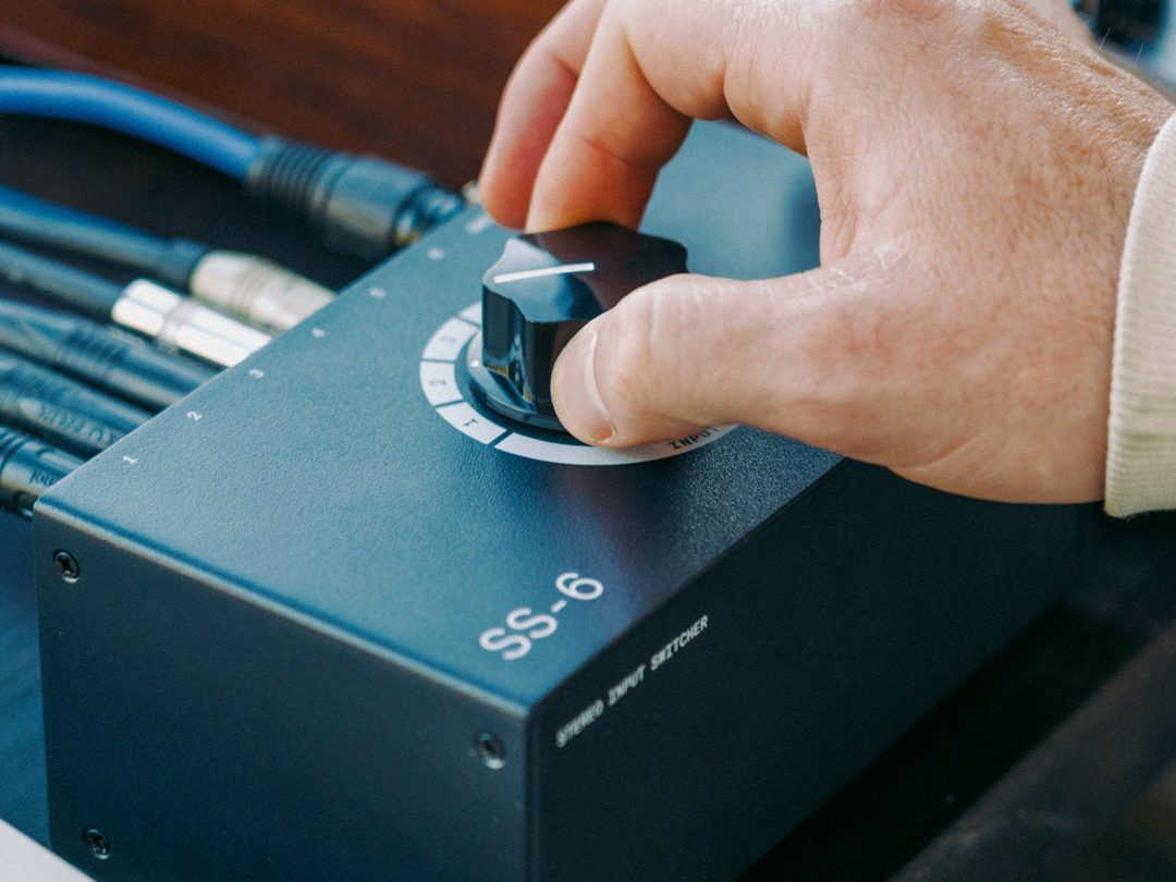 Mano girando la perilla del selector Franklin SS-6 MKII, con cables XLR conectados