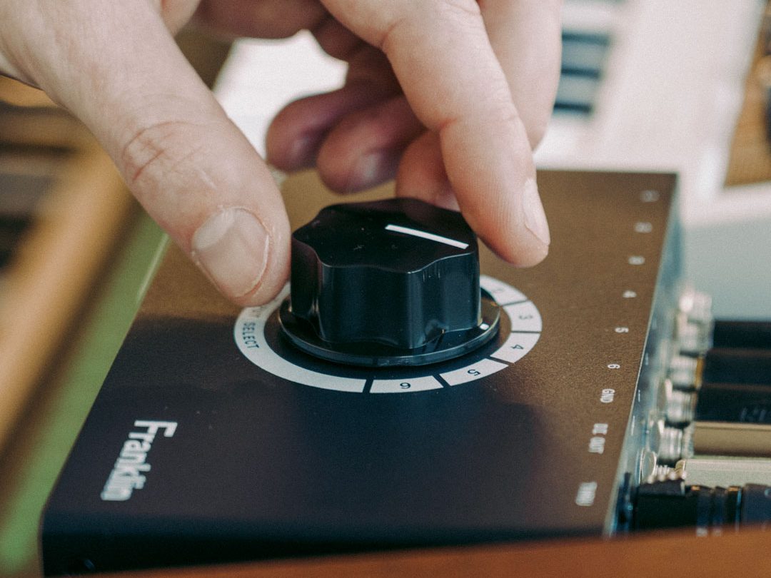 Mano girando el selector de entradas del Franklin SS-6 MKII junto a un teclado