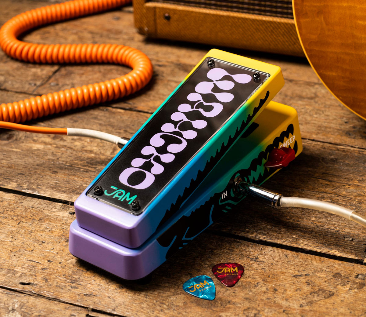 Wah JAM Wahcko mk.2, morado con detalles amarillos y verde azulado, sobre un piso de madera con un cable naranja