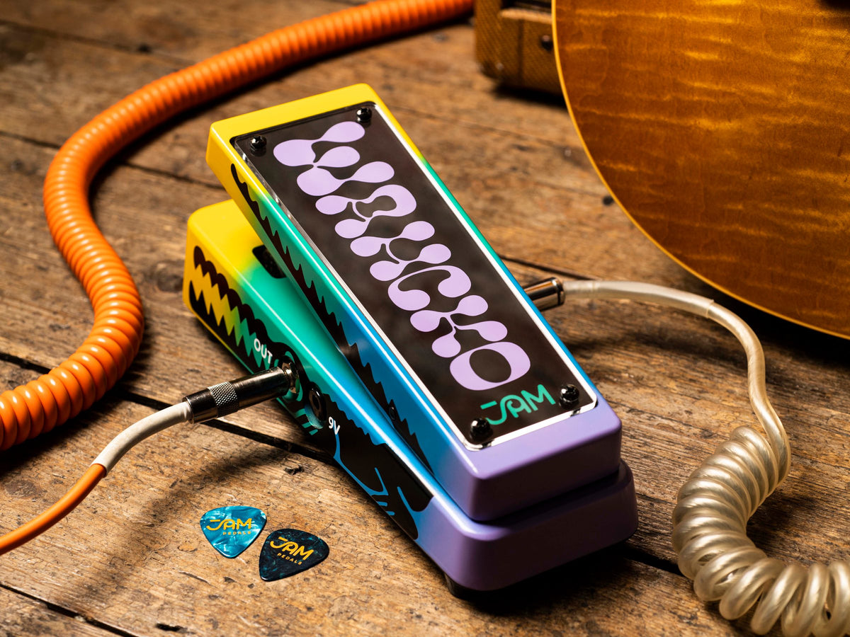 Wah JAM Wahcko mk.2 sobre madera, con un cable naranja enrollado y uñetas