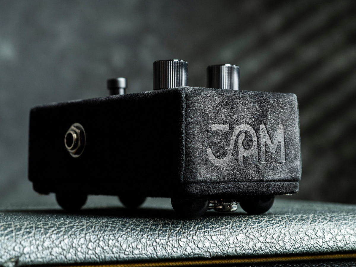 Pedal JAM Black Fuzz Phrase LTD, negro y de terminación texturizada, sobre un amplificador