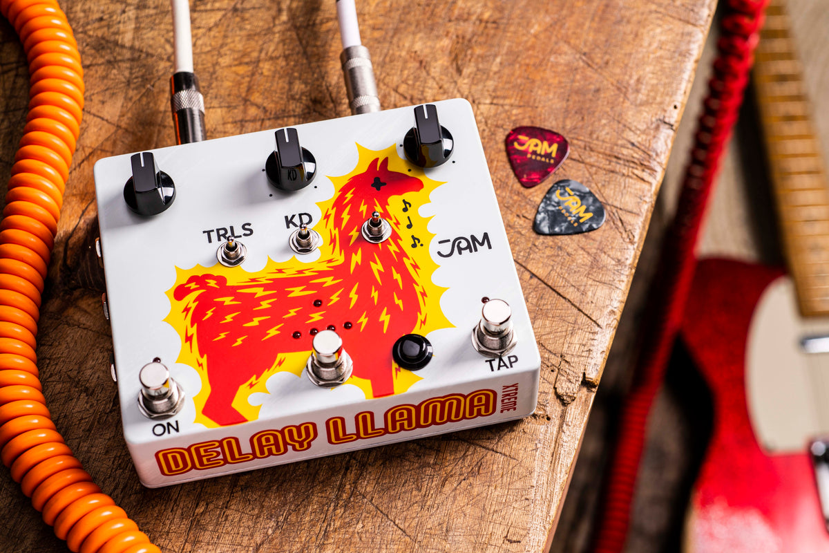 JAM Pedals Delay Llama XTREME sobre madera con un cable naranja en espiral