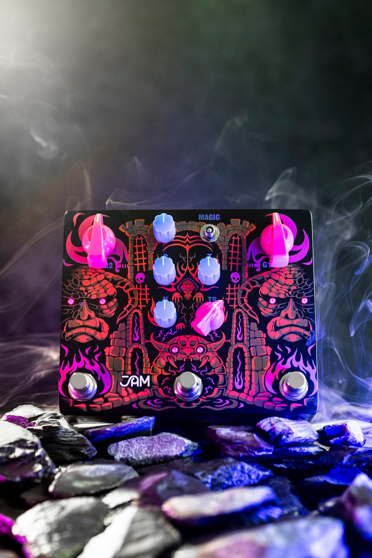 JAM Pedals Tiny Amp Destroyer en vertical sobre piedras con luz azul y púrpura