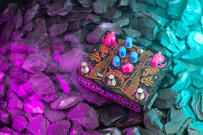 JAM Pedals Tiny Amp Destroyer sobre piedras iluminadas en púrpura y cian
