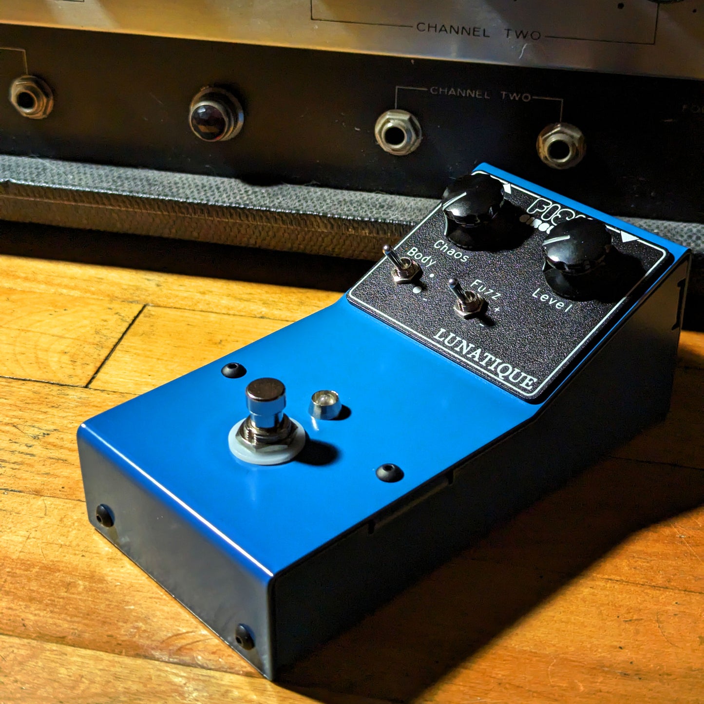 Fish Circuits Lunatique gated fuzz junto a un amplificador vintage, vista lifestyle