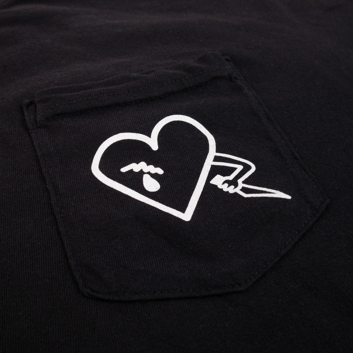 Detalle del bolsillo de la polera Make Noise QMMG con el corazón estampado en blanco